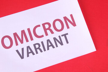 Face mask on a red background with a variant of the inscription Omicron. Omicron variant of the Covid19 virus