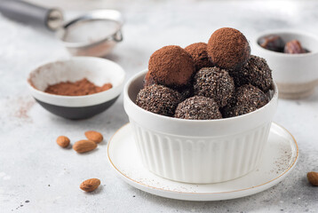 Vegan energy bliss balls in white bowl. chocolate truffles with dates, nuts, chia seeds