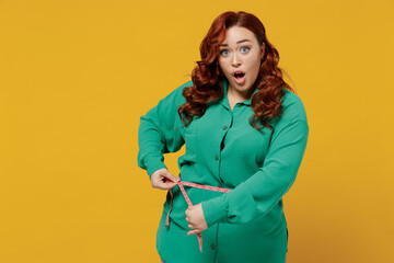 Shocked dissatisfied sad young ginger chubby overweight woman 20s years old wears green shirt hold...