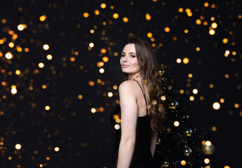 Beautiful young woman at the Christmas tree. An elegant woman.