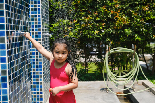little child girl stand taking a shower after playing in swimming pool