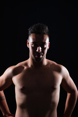 Fototapeta na wymiar Young caucasian man shirtless in a photography studio with a backlight and a black background.