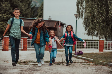 A group of students with protective masks on their faces run around the schoolyard while holding hands. Selective focus