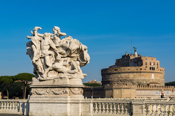 Statue on Vittorio Emanuele II bridge on Tiber river with the Castel Sant'Angelo (Castle of the Holy Angel) in background, Rome, Italy