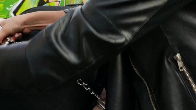 Policeman girl handcuffs the hands of the criminal, close-up of the hands. car bonnet arrest