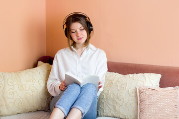 Beautiful young woman listening to audiobook at home. Happy girl wearing headphones listen to calm music in living room
