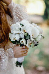 Wedding flowers, white color, bridal bouquet closeup. Decoration made of orchids close-up, selective focus, one person, unrecogizible