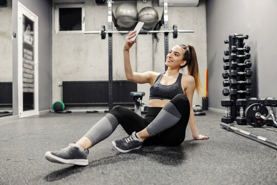 Fitness and social networks. A beautiful self-care girl in sportswear takes photos of herself during training. She posts photos and videos from the training on social networks. Online exercise