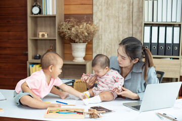 Busy woman trying to work while babysitting two kids.  Young Asian mother talking and playing with two children playing around her . Working women with multitasking.