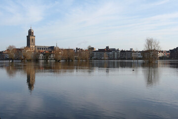 Obraz premium A view on the old buildings and the Great Church in the city of Deventer, the Netherlands, with reflection in a flooded meadow 