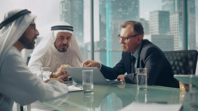 International Business Consultant Advices on Diversification of Investment Portfolio to Successful Arab Company Owners. Multicultural Meeting in Modern Office Between European and Emirati Businessman