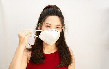 Asian Beautiful woman wear red red dress with sleeveless are wearing white mask to prevent from cold or a fever or COVID19 virus.
