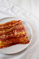 Homemade Oven Baked Bacon on a Gray Plate, side view. Copy space.