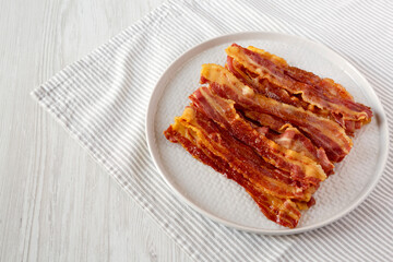 Homemade Oven Baked Bacon on a Gray Plate, side view. Space for text.