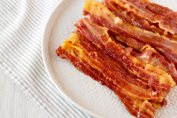 Homemade Oven Baked Bacon on a Gray Plate, side view. Copy space.