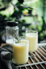 Corn juice smoothie on white rack placed on wood and plant backdrop in home garden pots. vertical photo