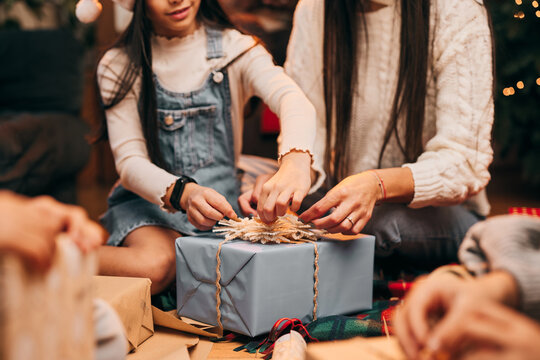 Close up of mother and daughter decorating Christmas gifts while sitting on the floor at home. Christmas and New Year concept.