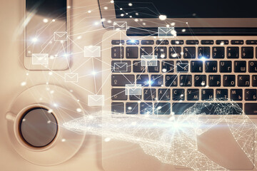 Envelop hologram drawing over computer on the desktop background. Top view. Double exposure. Technology concept.