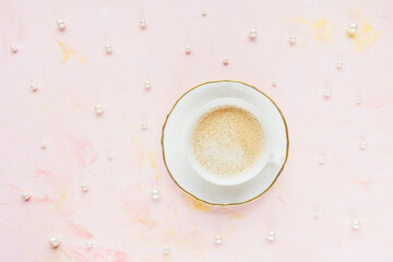 Cup of espresso on pastel pink with pearls abstract woman background. Drinking coffee, coffee break concept. Top view, flat lay, copy space
