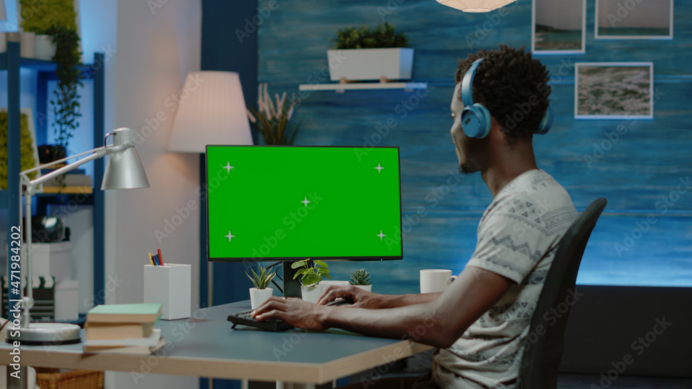 Poster entrepreneur working on computer with horizontal green screen. man wearing headphones, using chroma 