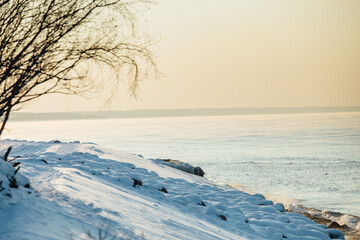 Winter color sunset at sea. A bright color sunset by the sea on a winter day. The beach is snowy. People walk along the sea. The beach is snowy.