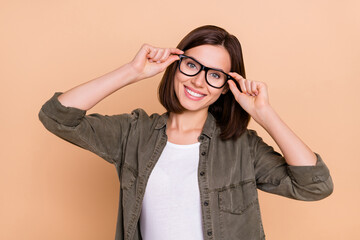 Photo of cheerful lady hold eyeglasses beaming smile wear khaki shirt isolated beige color background