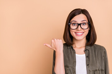 Photo of excited funny lady indicate thumb empty space promotion variant wear khaki shirt isolated...