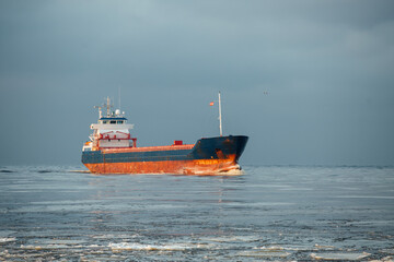 A small ship enters the port. Bulk carrier.