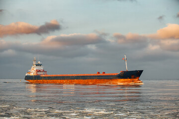 A small ship enters the port. Bulk carrier.
