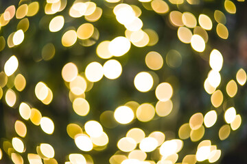 Abstract blurred bokeh light on a Christmas tree with a warm shade of yellow and green. Beautiful New Year background 2022.