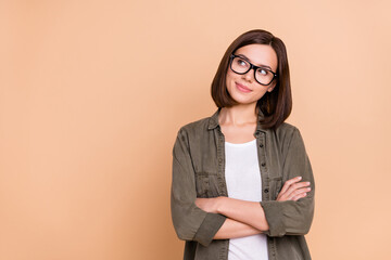 Photo of curious lady folded hands look empty space wear eyeglasses khaki shirt isolated beige...