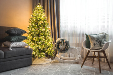 Cozy decor in gray-green tones in the interior of the Christmas room, a Christmas tree decorated with garlands, gifts, a wooden horse. A festive living room in the house. New Year's holidays 2022