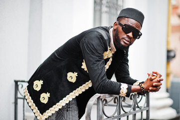 Mega stylish african man in traditional jacket pose. Fashionable black guy in hat and sunglasses...