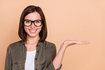 Photo of positive lady palm presenting empty space solution option wear specs khaki shirt isolated...
