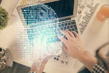 Double exposure of man's hands typing over computer keyboard and brain hologram drawing. Top view. Ai and data technology concept.