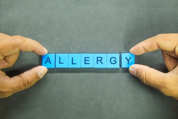 hand holding a blue square with the word allergy
