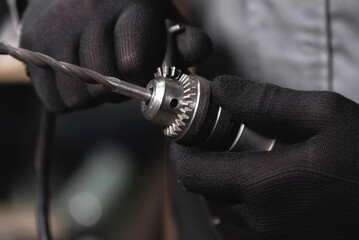 Worker twists the drill bit into the drill with a wrench.