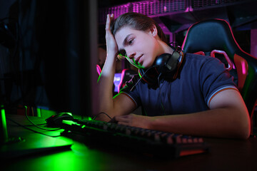 Professional young caucasian gamer playing online on his PC. He upset because of losing the game