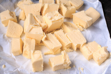 Fresh, organic Butter on white paper, dairy farm product. Dark background, top view.