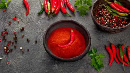 Red chili or chilli cayenne pepper and peppercorns on dark background.