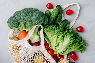 Mesh bag with vegetables. Organic broccoli, tomato, cucumbers, carrot, ginger, lettuce and potato in cotton shopper bag