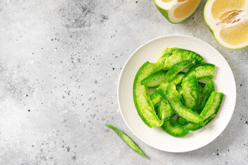 Dried pomelo slices in a white bowl on a light gray background. A healthy citrus fruit snack for weight loss and healthy eating. Top view. Copyspace	