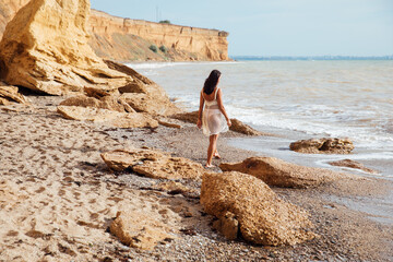woman walking on a sandy beach by the sea waves