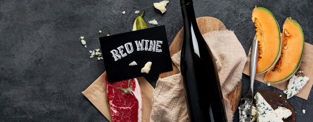 Red wine with appetizers on gray background.
