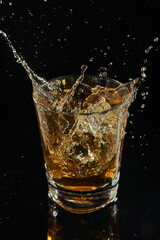 glass of whiskey into which ice falls. frozen splashing drops