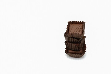 Chocolate candies in paper cups on a white background.  Stack of chocolate sweets in brown paper cups. Craft chocolate in Ukraine. Copy space. 