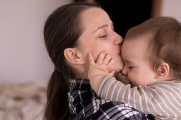 Portrait Adorable Face Of Little Cheerful Happy Toddler baby girl child With Charming Smile Look At Mom Strong Cuddles Loving Mommy Together. Mother Hugs play love care kiss smiling daughter at home