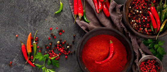 Red chili or chilli cayenne pepper and peppercorns on dark background.