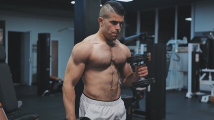 Fototapeta na wymiar Muscular arab man training with dumbbells in the gym.