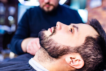 Obraz na płótnie Canvas hispanic bearded man having his hair cut by hairdresser at the barbershop